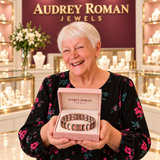 A white-haired woman presents the Clara Chain Bracelet in an Audrey Roman Jewels box inside the rose and ivory boutique.
