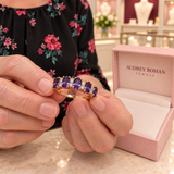 Hazel Purple Crest Ring (rose-gold-tone) held in the woman's hands for a close detail view inside the Audrey boutique.