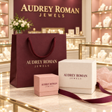 Wine-colored Audrey Roman Jewels shopping bag with ivory and rose boxes on the boutique counter.