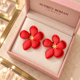 Overhead view of Cassandra red flower earrings in the Audrey Roman Jewels box on the boutique counter.