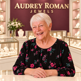 A white-haired woman behind the counter in the rose and ivory Audrey Roman Jewels boutique.